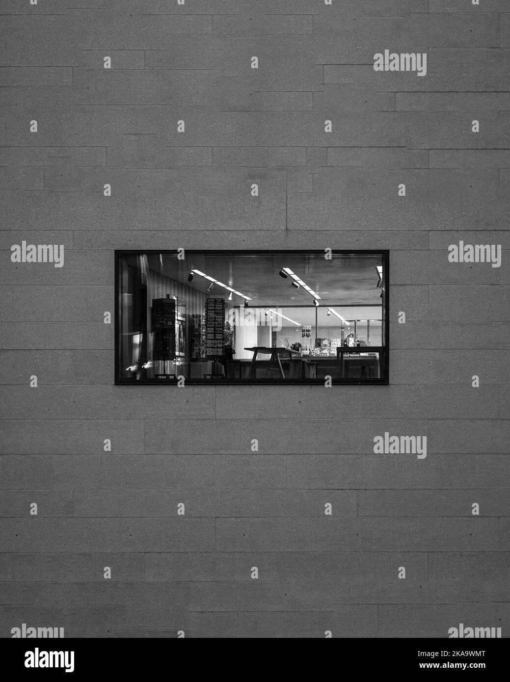 A vertical grayscale shot of a window with a view of the inside of a store. Stock Photo