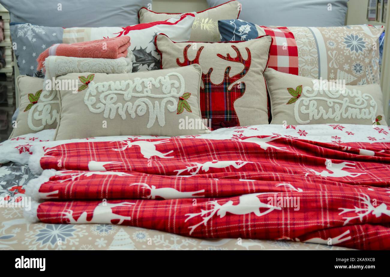 Moscow, Russia, November 2019: Christmas bedding: bed linen, red deer plaid, blanket with snowflakes, decorative pillows with the inscription Merry Ch Stock Photo