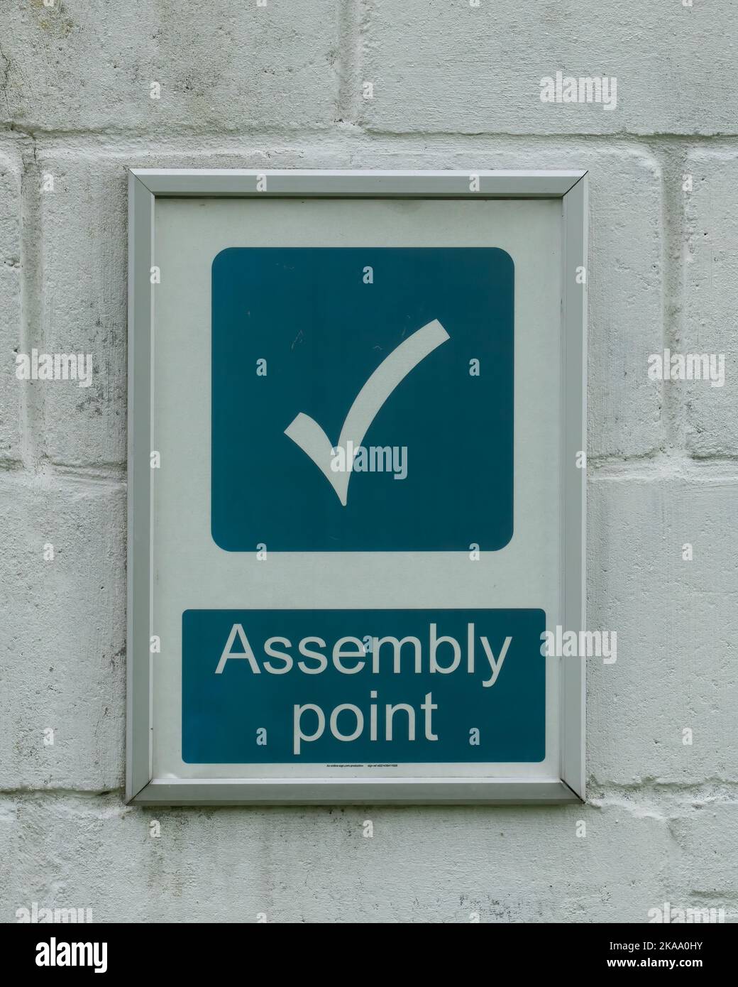 Steel Frame Assembly Point Sign A vertical shot of a framed Assembly point sign on white brickwork wall ...