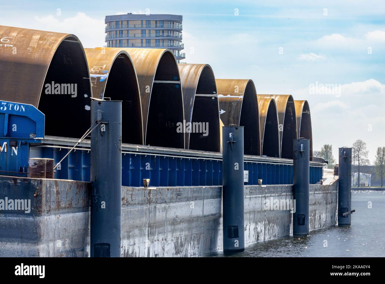 A closeup of barges with monopiles in an industrial harbor in Roermond Stock Photo