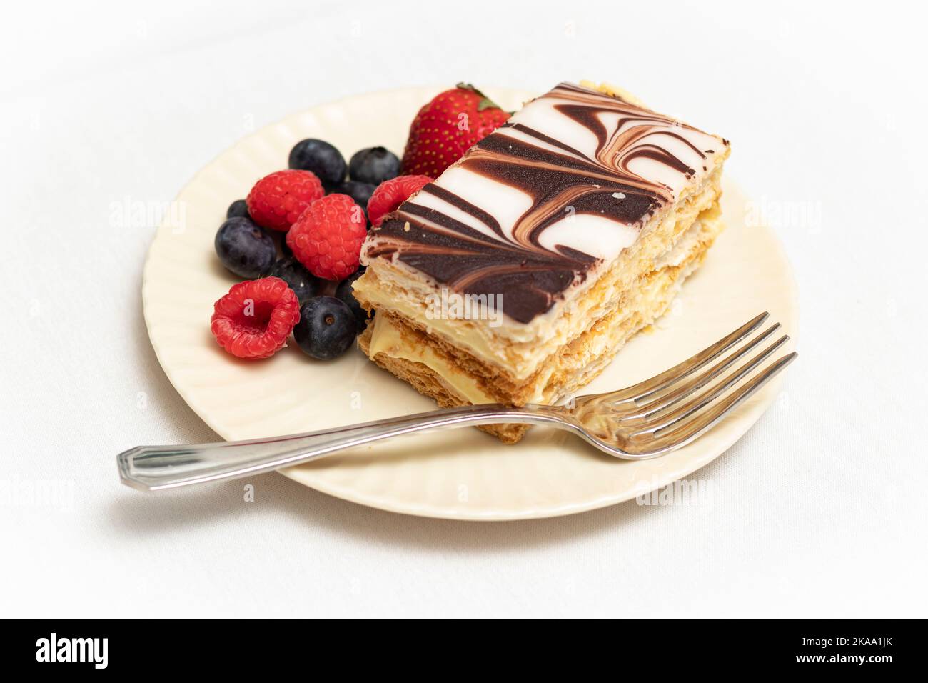 Napoleon dessert pastry and colorful mixed berries plated with silver fork. Stock Photo