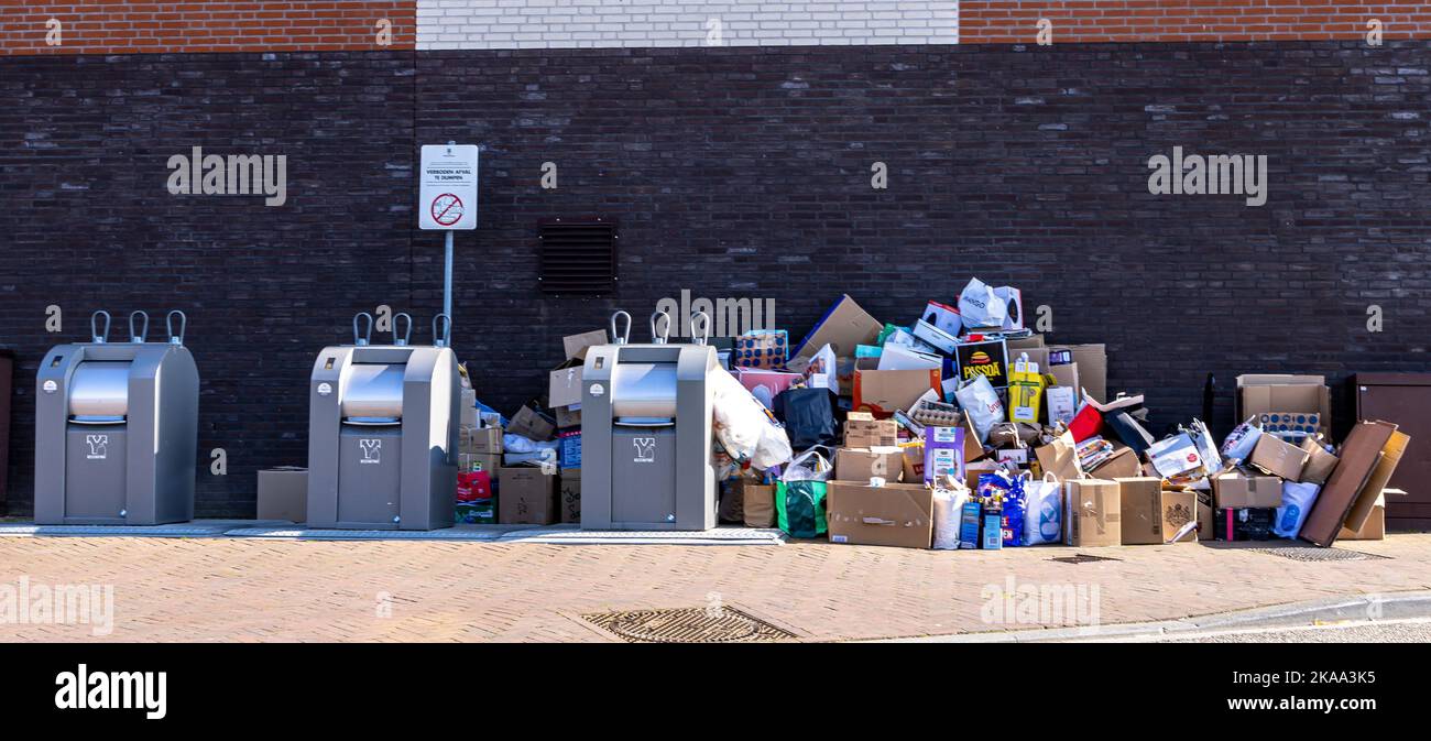 Three metallic underground trash collection bins outside a wall in