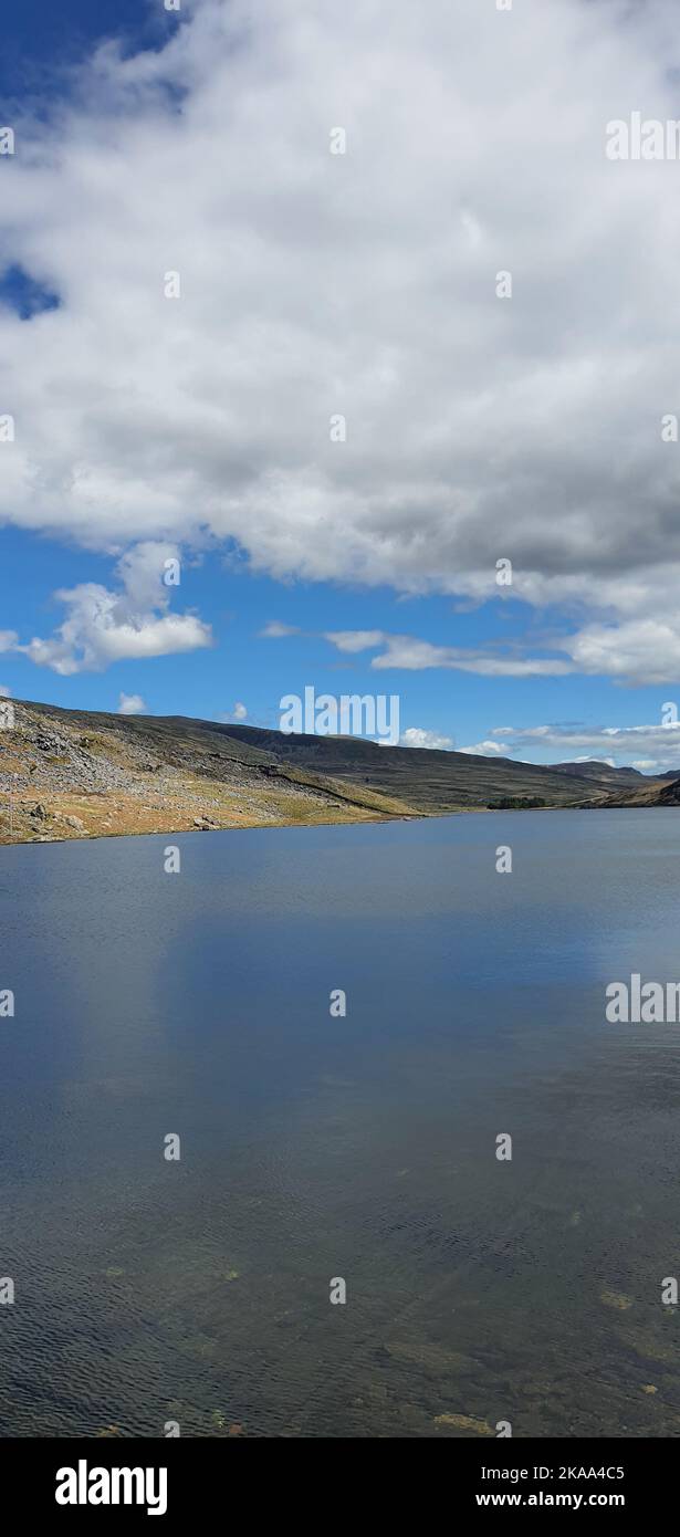 A vertical shot of the cloudy blue sky over the calm lake on a sunny ...