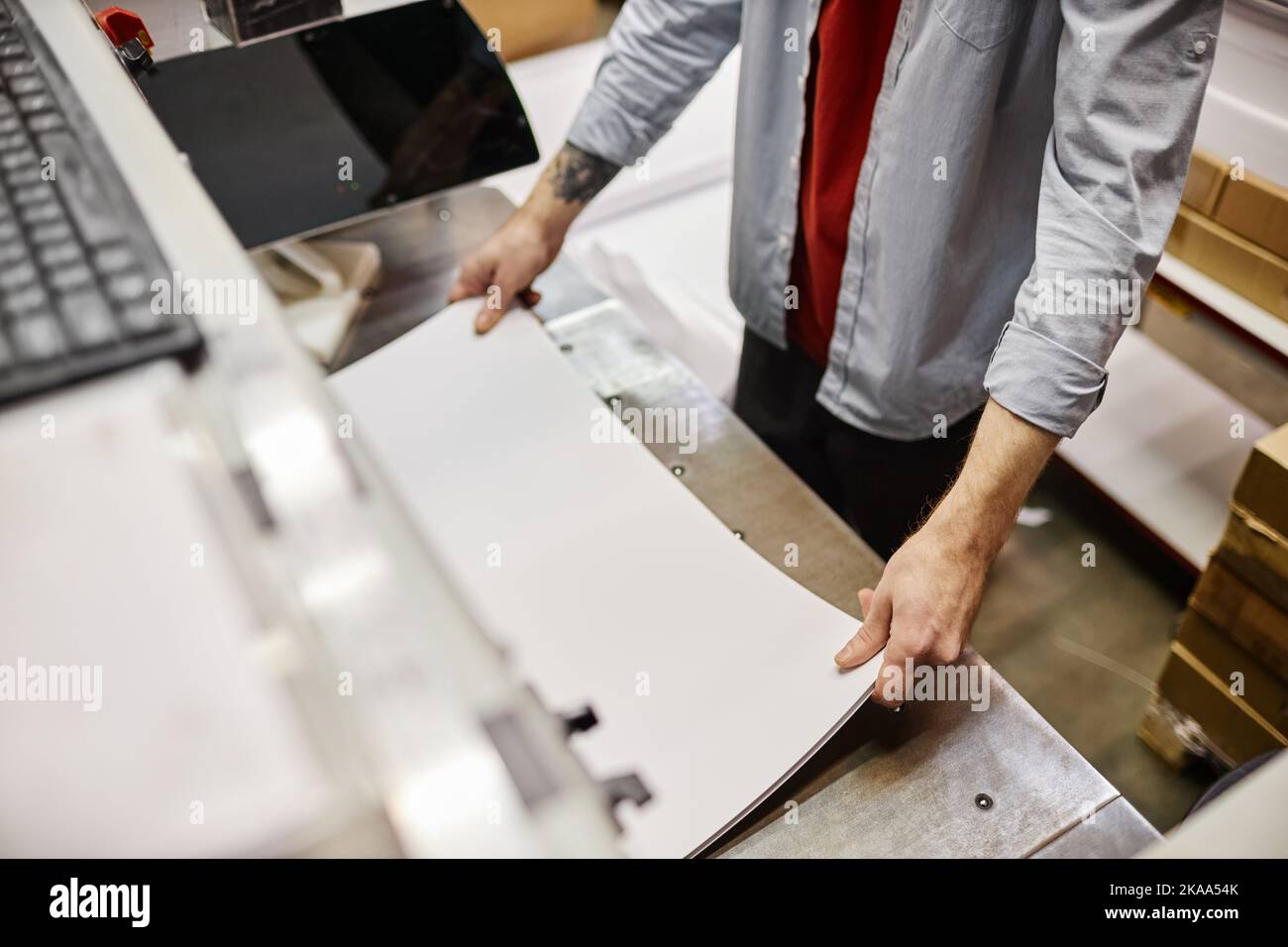 High angle view of man putting stack of paper in printing machine at publishing shop, copy space Stock Photo