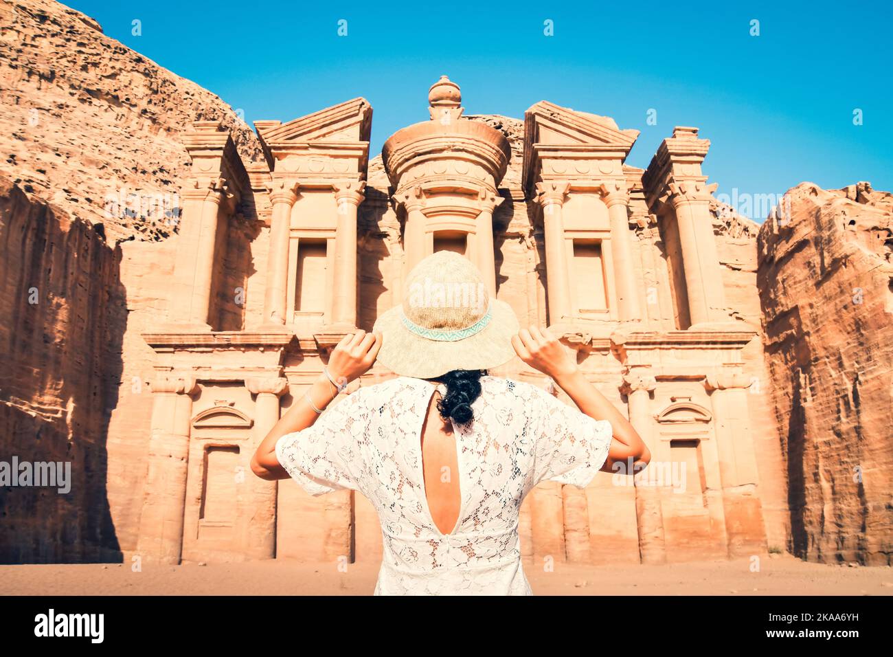 Caucasian woman tourist in white dress hold her white hat pose at Ad Deir or El Deir, the monument carved out of rock in the ancient city Petra, Jorda Stock Photo