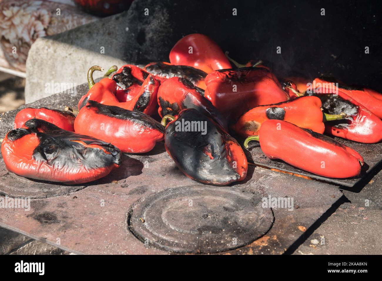 Roasting red bell peppers on outdoor fire pit of farmhouse Stock Photo