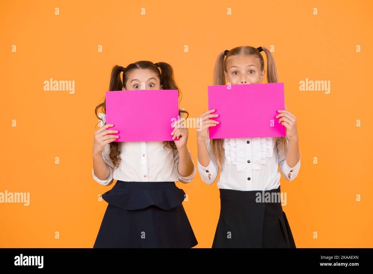 Drawing attention. Happy kids holding empty sheets of paper. Little kids smiling with pink drawing papers. Small kids smiling with blank advertisement Stock Photo