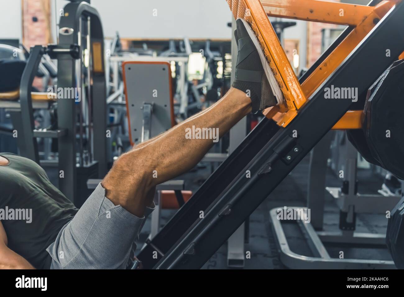 Professional gym leg press used by unrecognizable caucasian person in gray shorts. Body muscles building process. Leg day. High quality photo Stock Photo