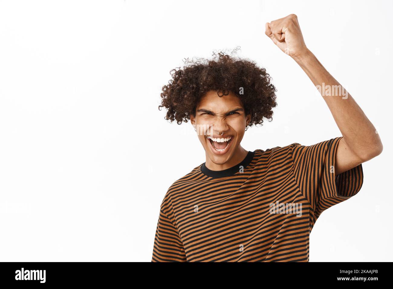 Close up portrait of cheerful young man full of excitement, raising ...