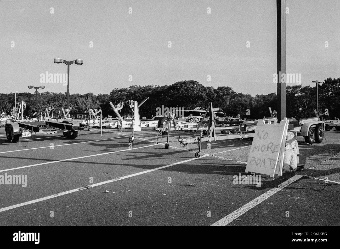 A sea of boat trailers in a parkinglot with a sign the reads No More Boats in Rockport, Massachusetts. The image was captured on analog black-and-whit Stock Photo