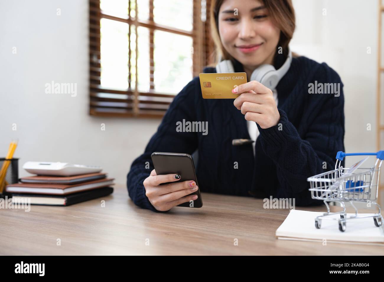 Asian girl making online payment using mobile phone for shopping at home. Stock Photo