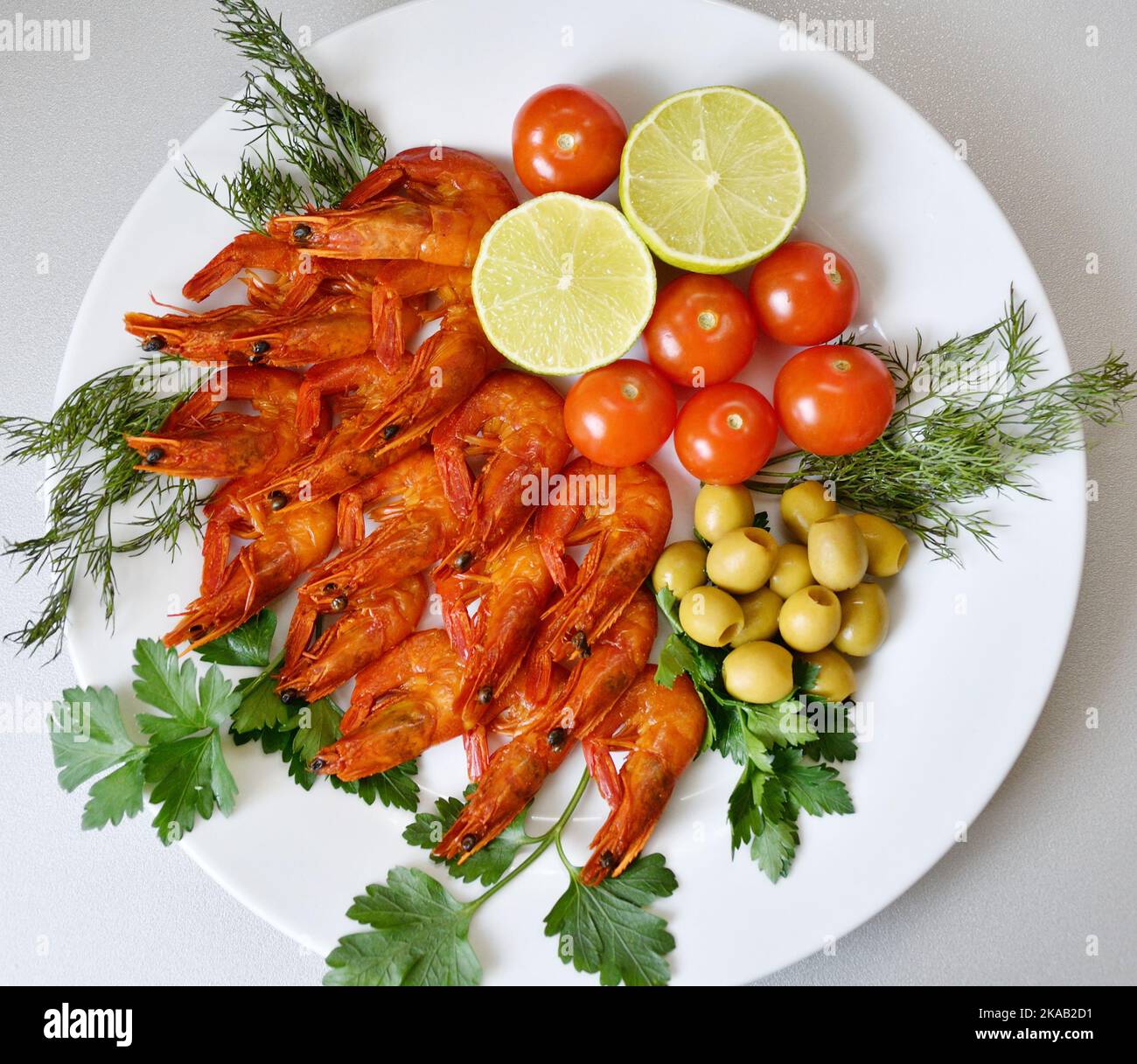 Cooked shrimp with fresh herbs, olives, lime and tomatoes Stock Photo