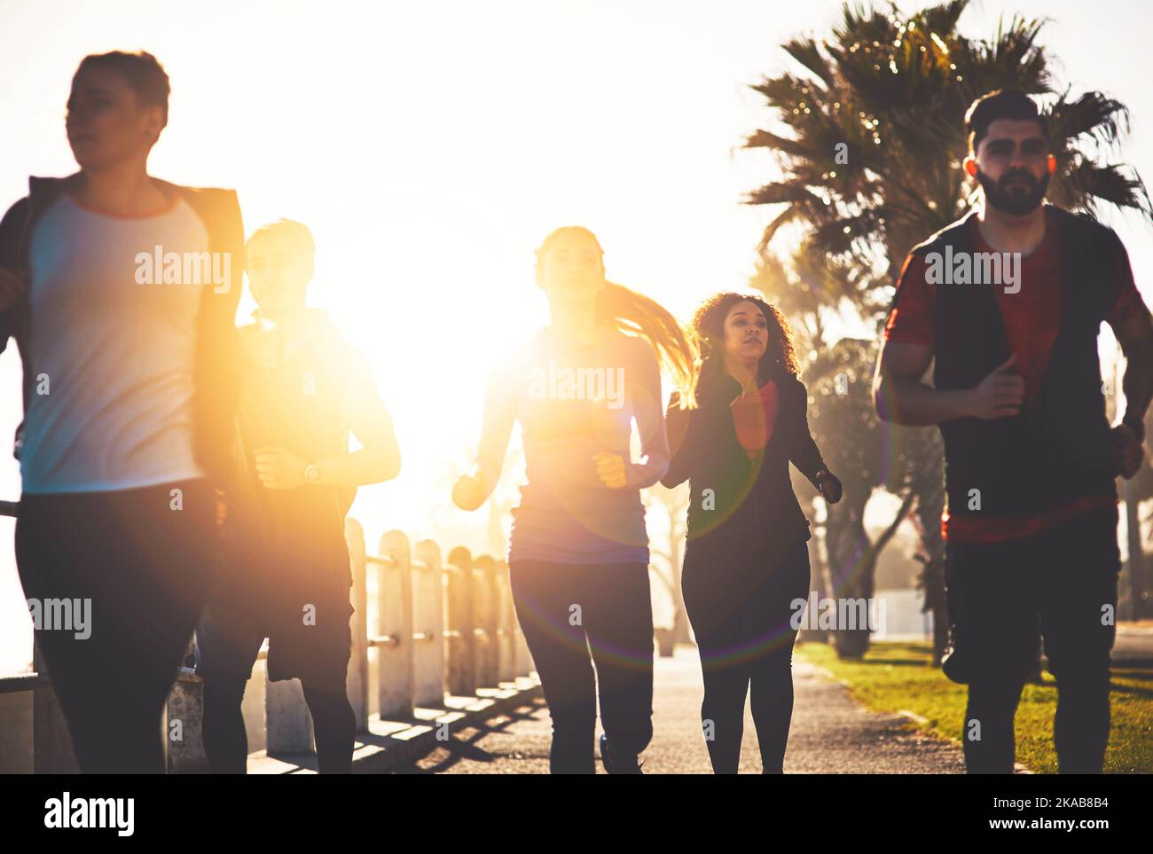 Seeing them push through is what motivates me. a fitness group out running on the promenade. Stock Photo