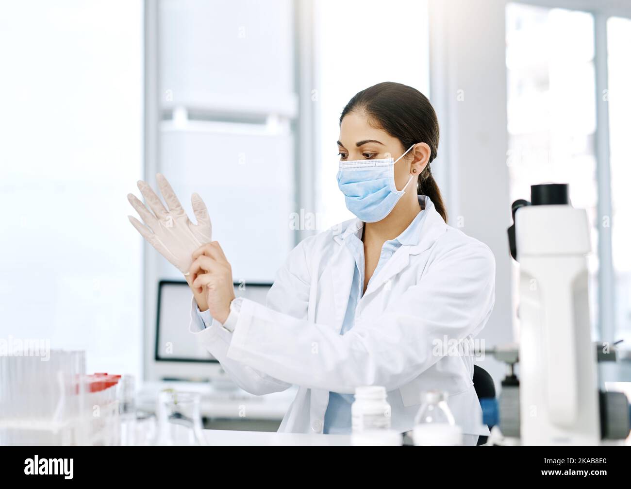 Lets get experimenting. a young scientist putting on surgical gloves while working in a lab