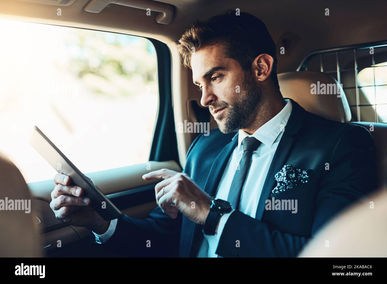 Email check before I get in. a handsome young corporate businessman using a tablet while commuting. Stock Photo