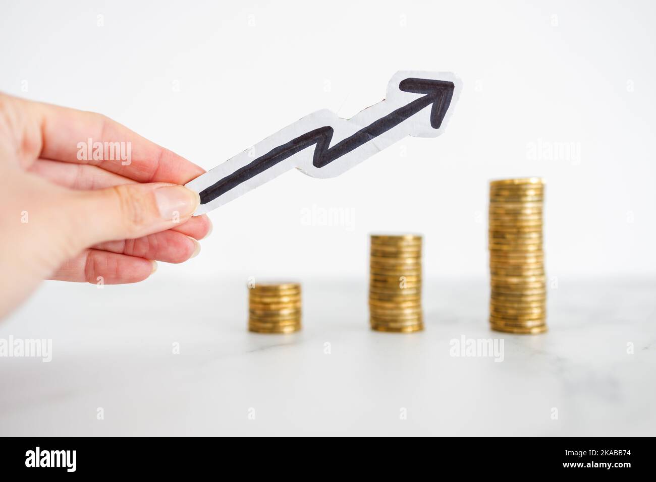 growing stacks of coins with arrow pointing upward, metaphor of