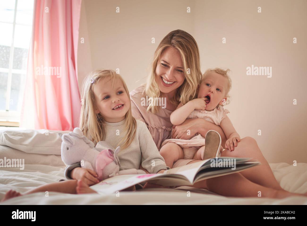 Its a time to learn and a time to bond. an adorable family of three reading a book together on the bed at home. Stock Photo