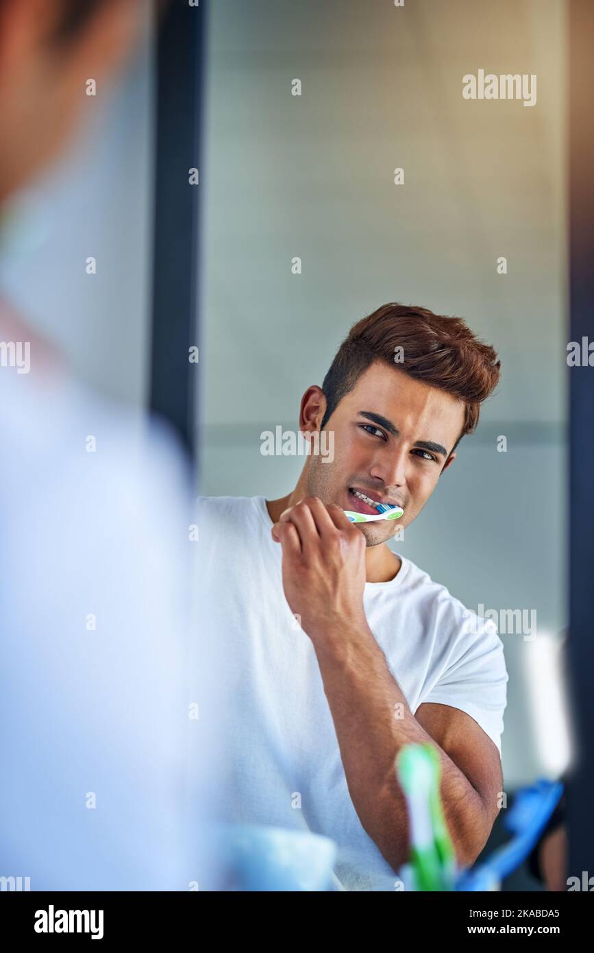 Getting tough on pesky plaque. Portrait of a happy young man brushing his teeth at home. Stock Photo