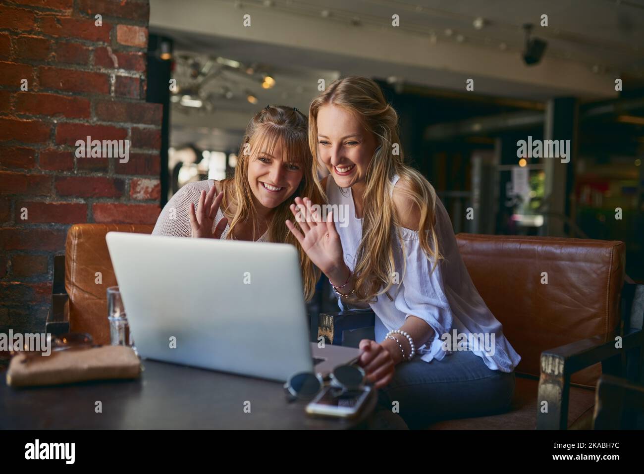 Can you see us. two attractive young girlfriends video chatting via laptop while sitting in a cafe. Stock Photo