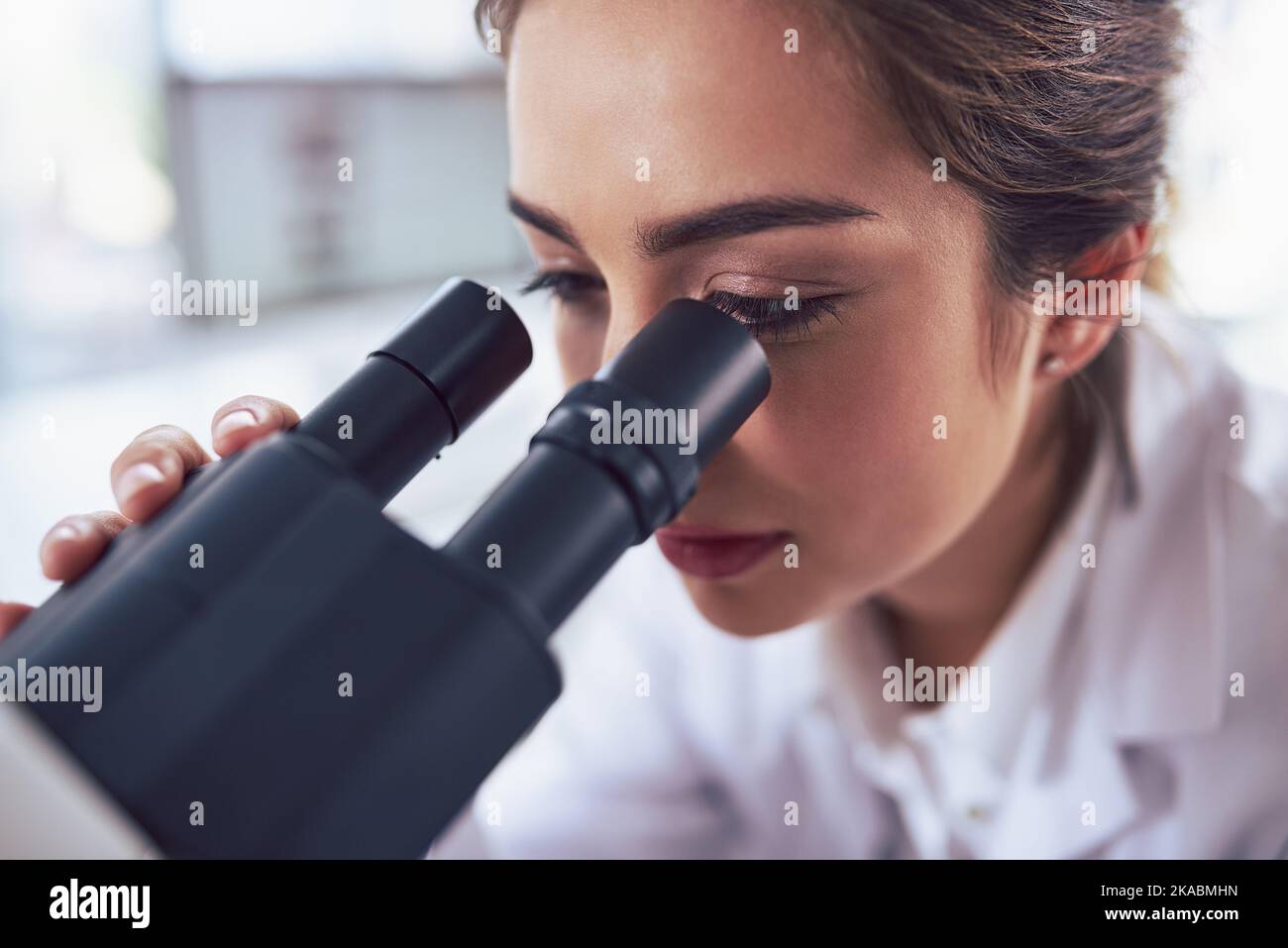 Zoomed in vision. Closeup of a focused young female scientist looking