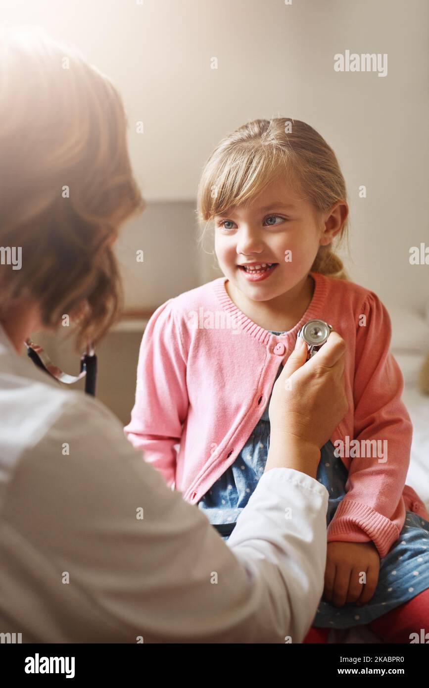 Breathe in for me. a doctor examining a little girl with a stethoscope ...