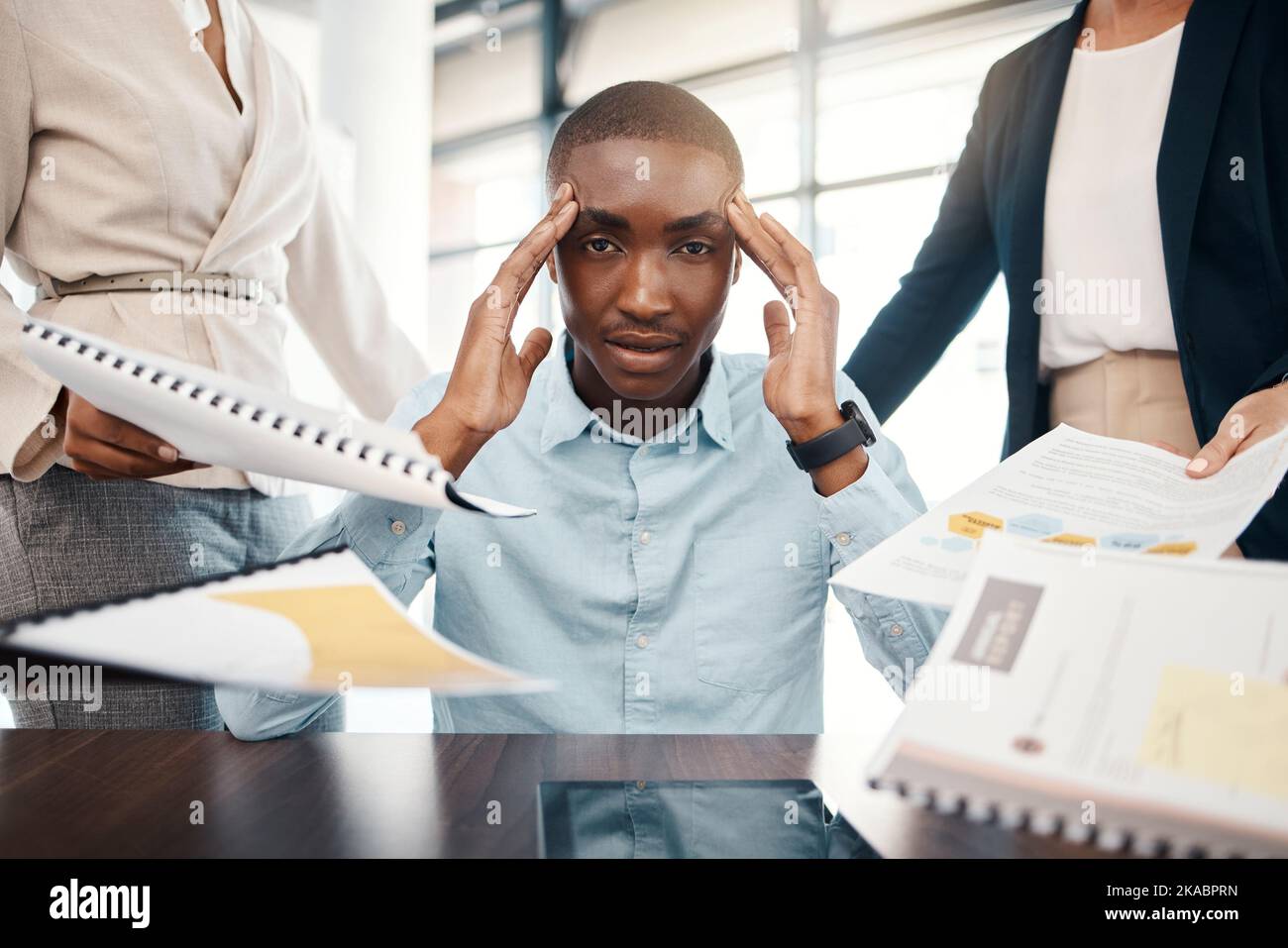 Headache, overwhelmed businessman and work report stress in office with team. Black man, stressed business management leader and corporate mental Stock Photo