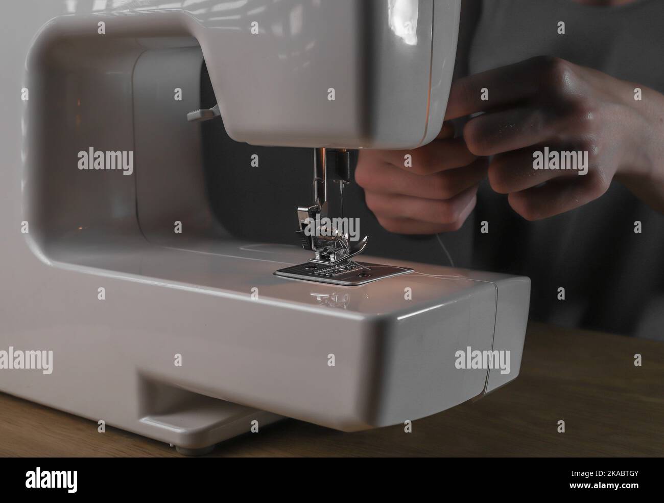 Hands inserting thread through needle hole in sewing machine, details