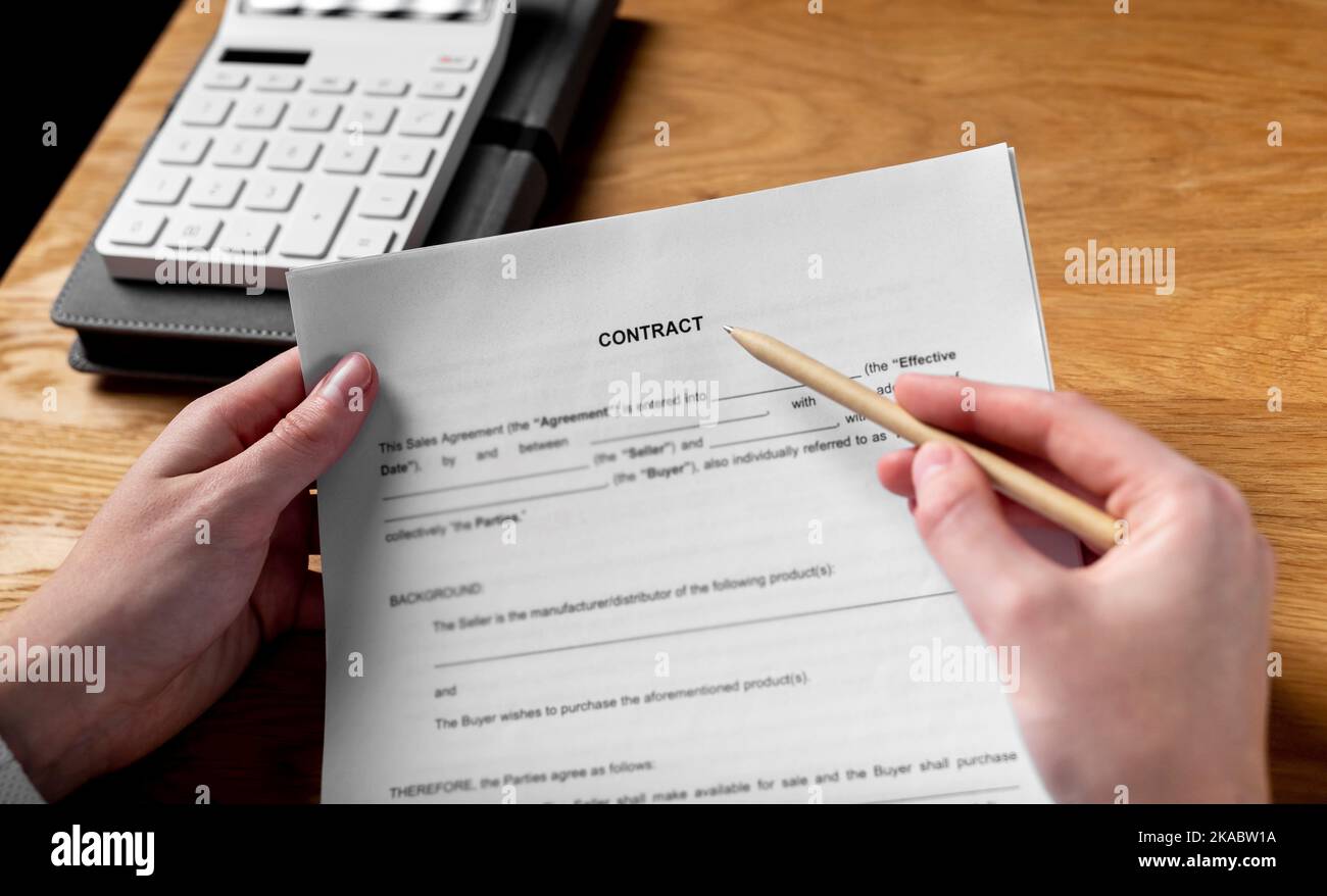 Paper sales contract on wood desk in female hands with pen. Stock Photo