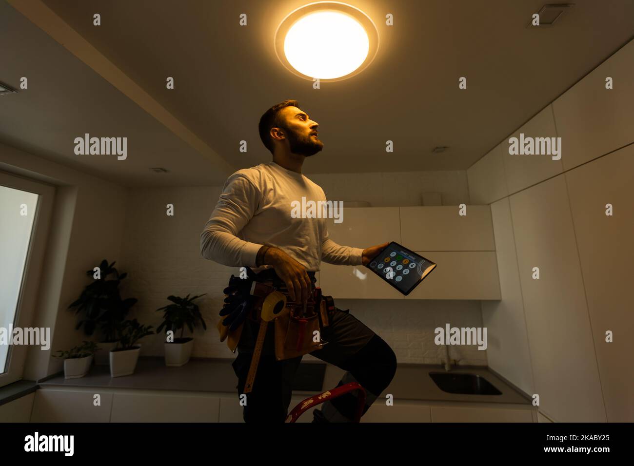 Installation lighting. Builder is holding a tablet in his hands. Concept - lighting engineer. Process installing. Electrician Stock Photo