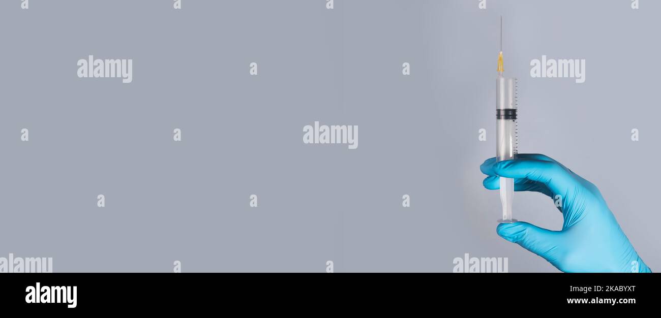 Syringe with needle in doctors hands in glove with copy space for medical advertisement Stock