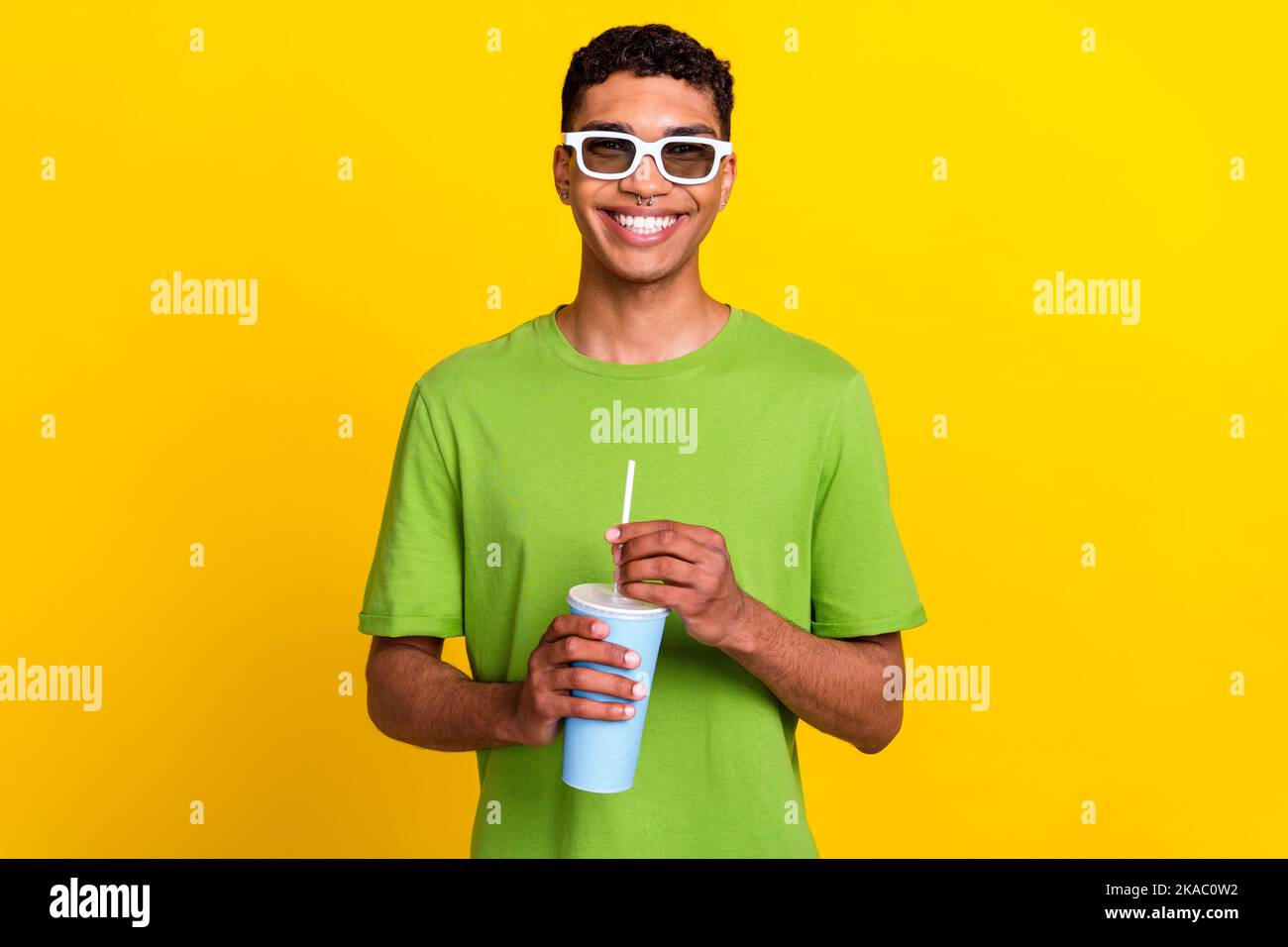 Porttrait photo of young positive attractive smiling man wear white glasses good mood hold soda cola drink emotion after cinema isolated on yellow Stock Photo