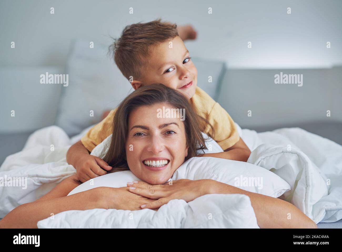 Young mother with 4 years old son in bed Stock Photo