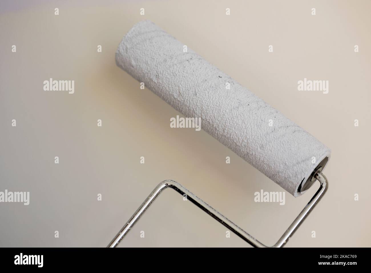 Paint roller loaded with white paint ready to use on the wall Stock Photo