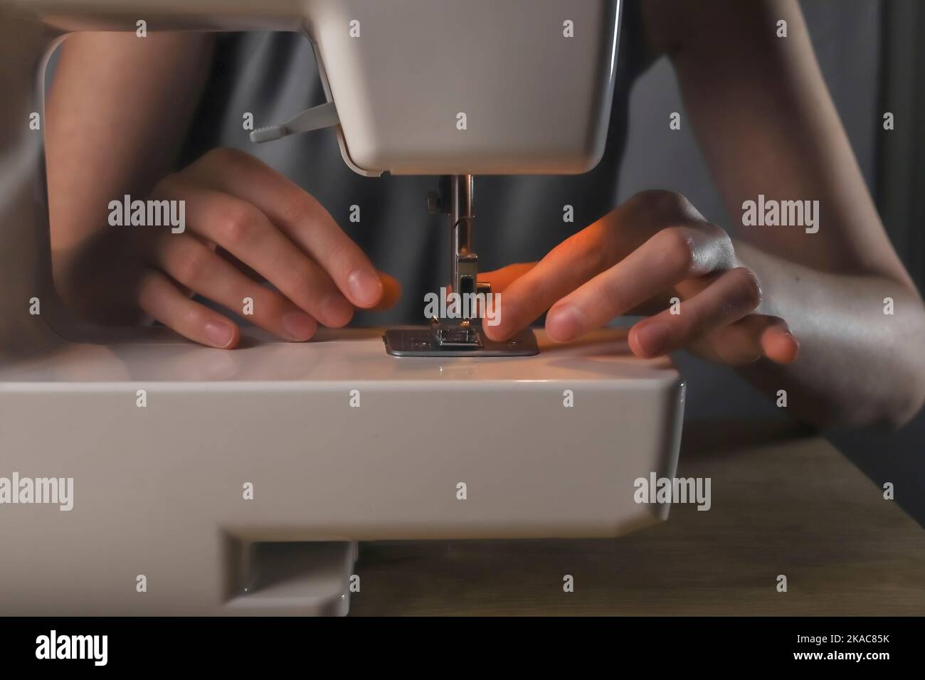 Hands inserting thread through needle hole in sewing machine, details