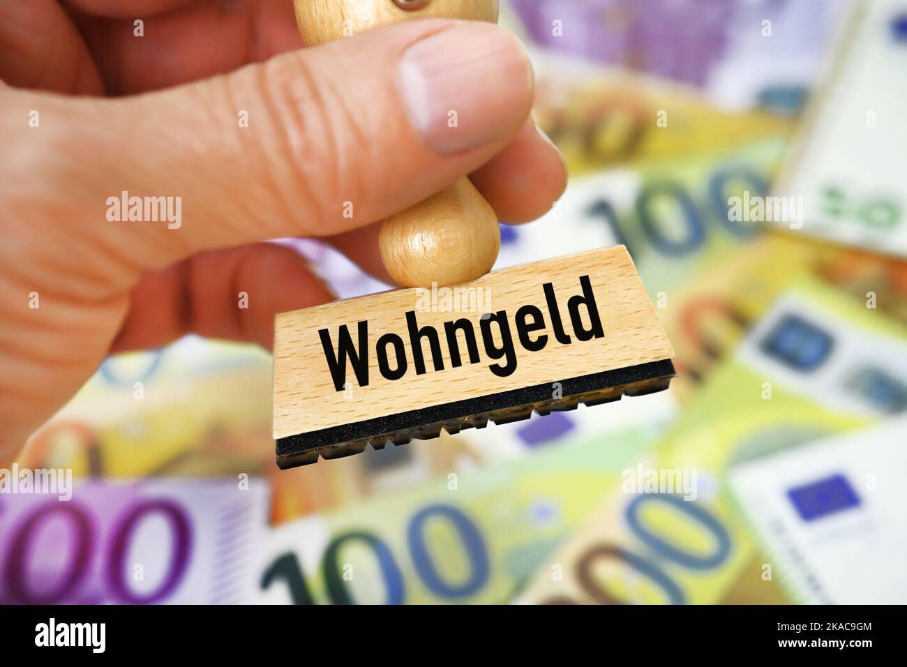 FOTOMONTAGE, Hand hält Stempel mit Aufschrift Wohngeld über Geldscheinen Stock Photo