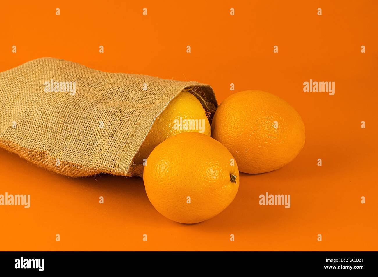 Oranges in a natural burlap bag on an orange background Stock Photo - Alamy