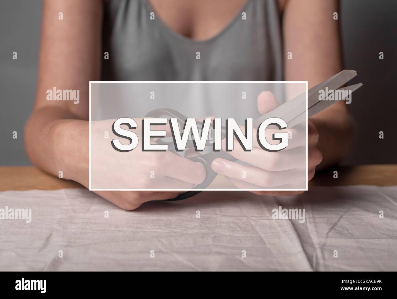 Word Sewing. Handicraft concept, hands with taylors scissors Stock