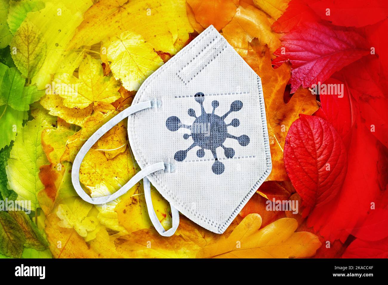 FOTOMONTAGE, FFP2-Maske auf Herbstlaub mit Coronavirus-Symbol, Symbolfoto Herbstwelle Stock Photo