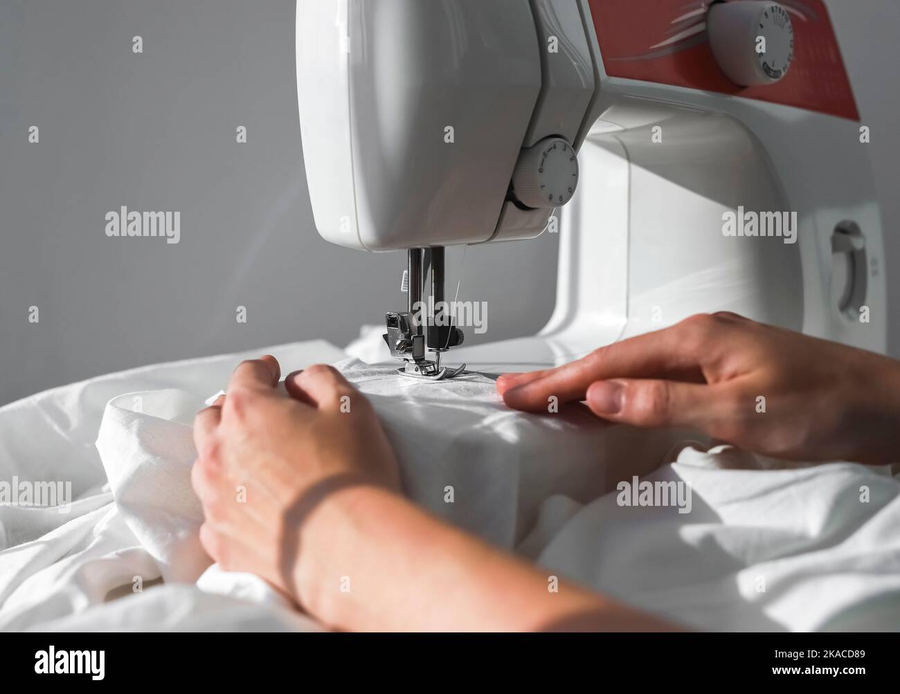 Female hands with natural cotton cloth working at sewing machine, Small