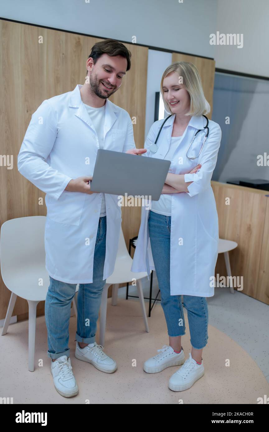 Joyous physicians in white lab coats standing in reception area Stock