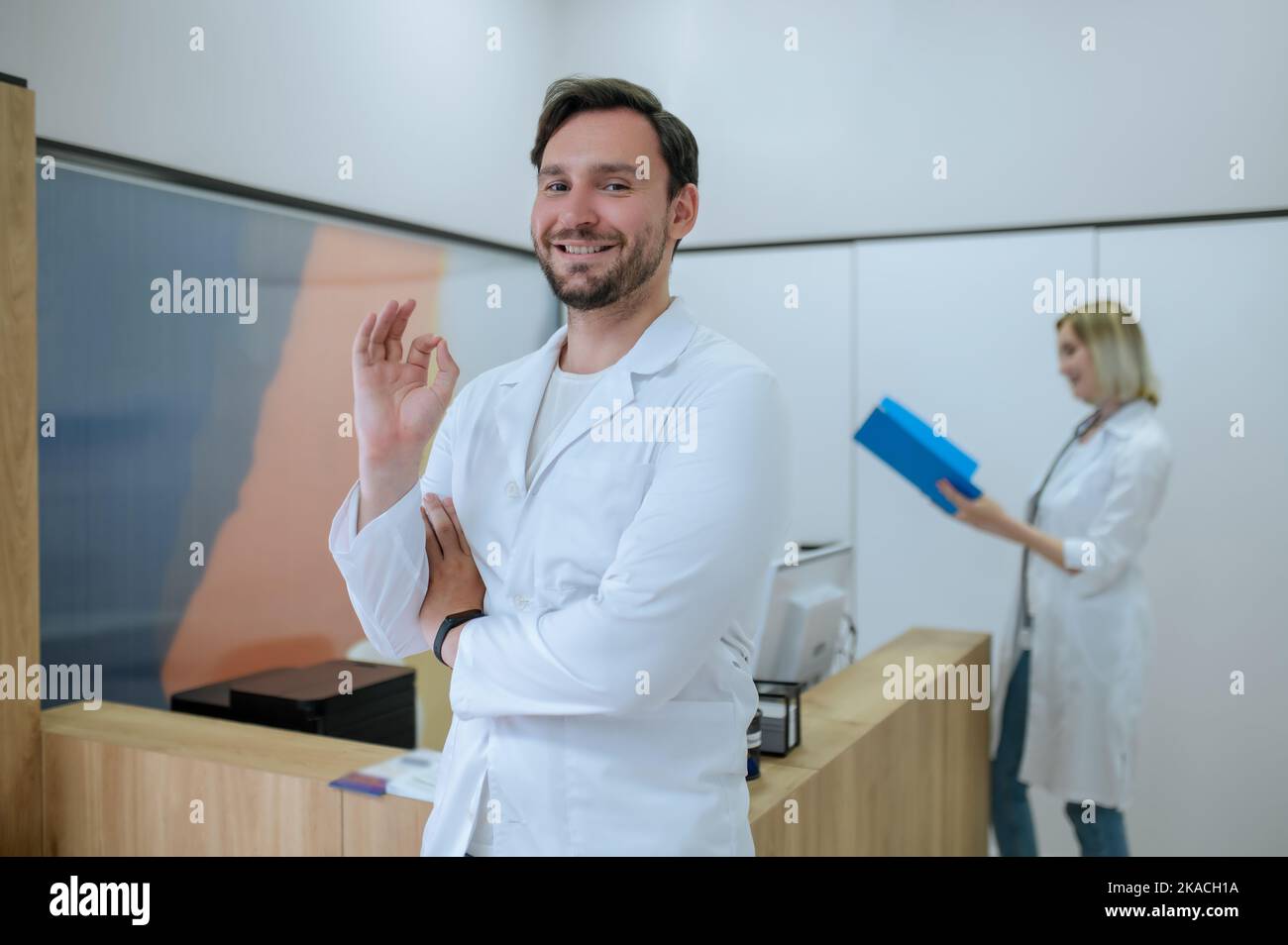 Clinic physicians in white lab coats standing at reception desk Stock