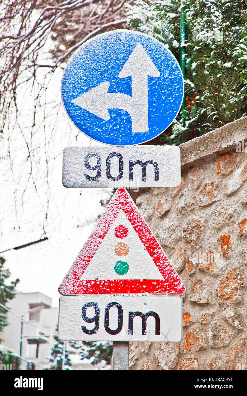 traffic sign covered with snow indicates traffic light in 90 meters ...