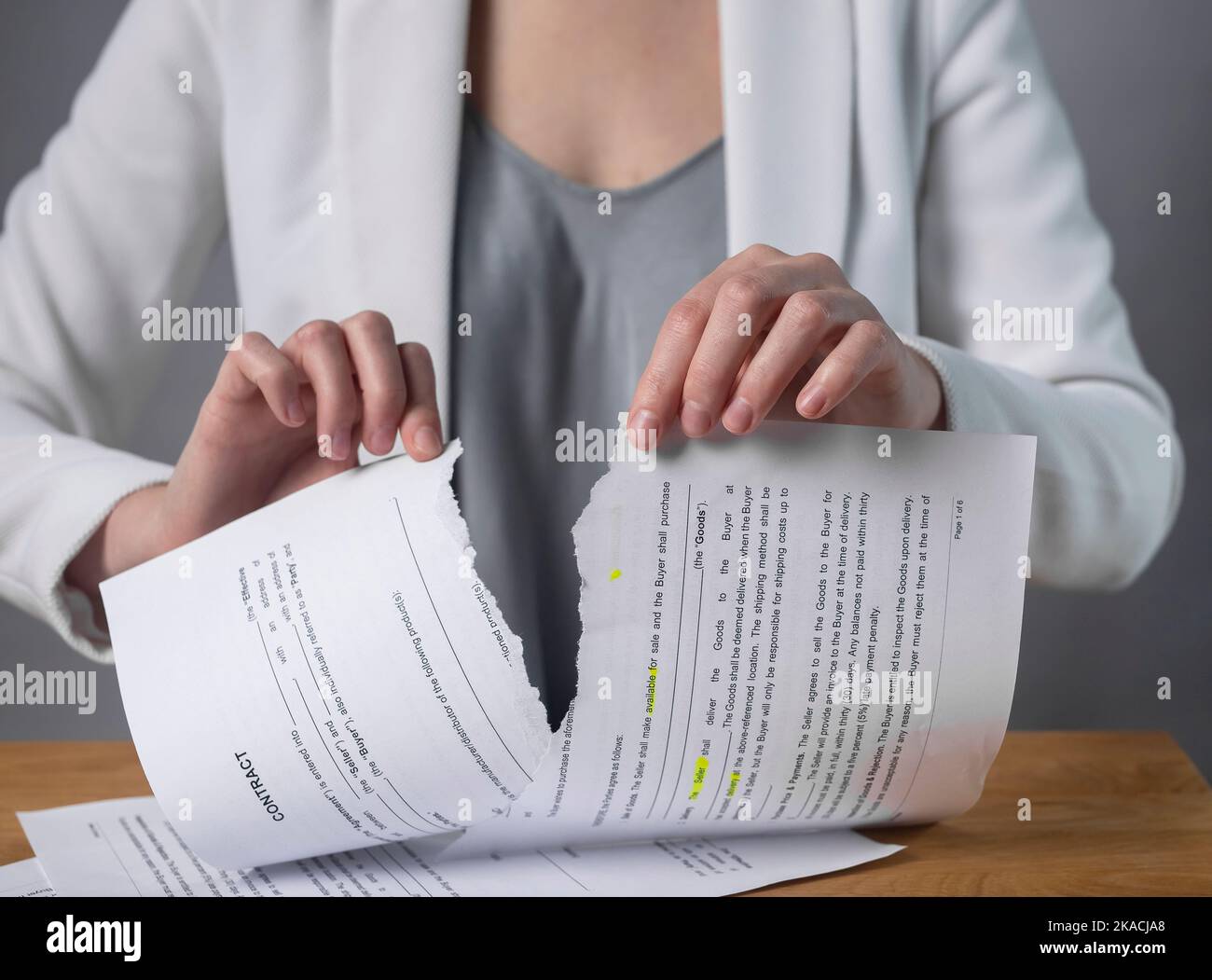 Torn contract in hands. Terminated agreement concept. Ripping paper document and breaching rules. Stock Photo