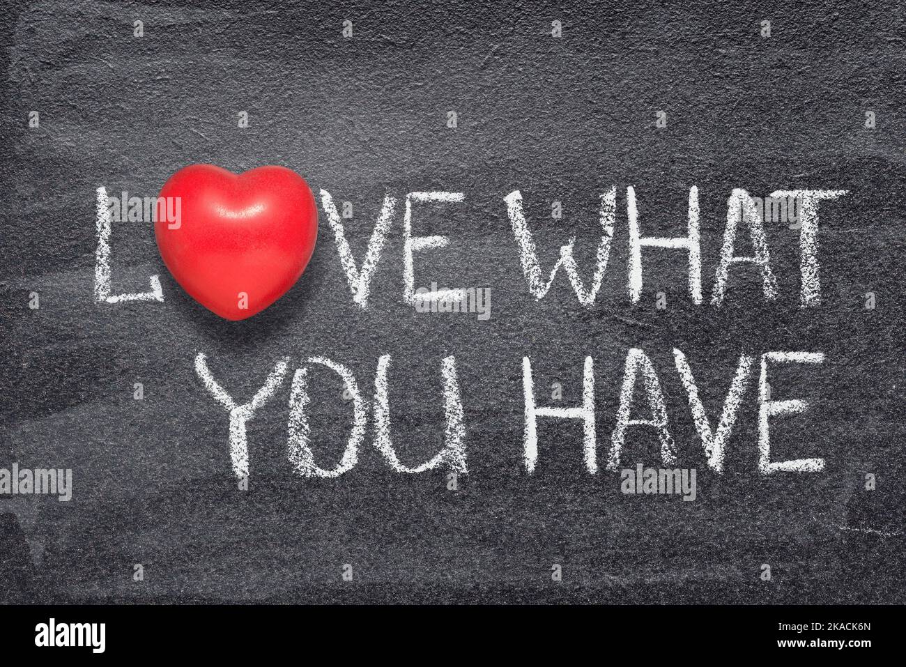 love what you have phrase written on chalkboard with red heart symbol instead of O Stock Photo