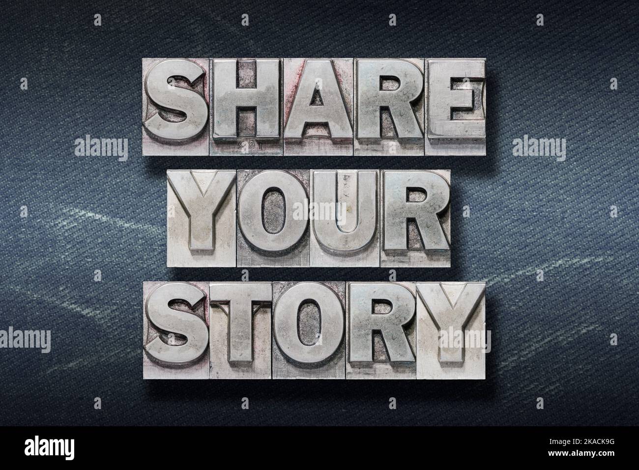 share your story phrase made from metallic letterpress on dark jeans background Stock Photo