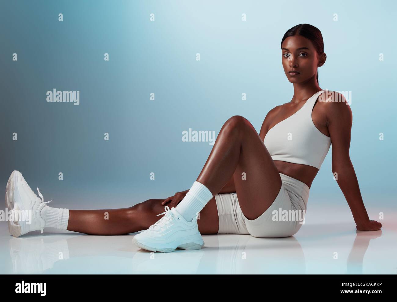 Fitness, woman and portrait in studio for health, exercise and body goals against a blue background mockup. Floor, workout and indian girl model with Stock Photo