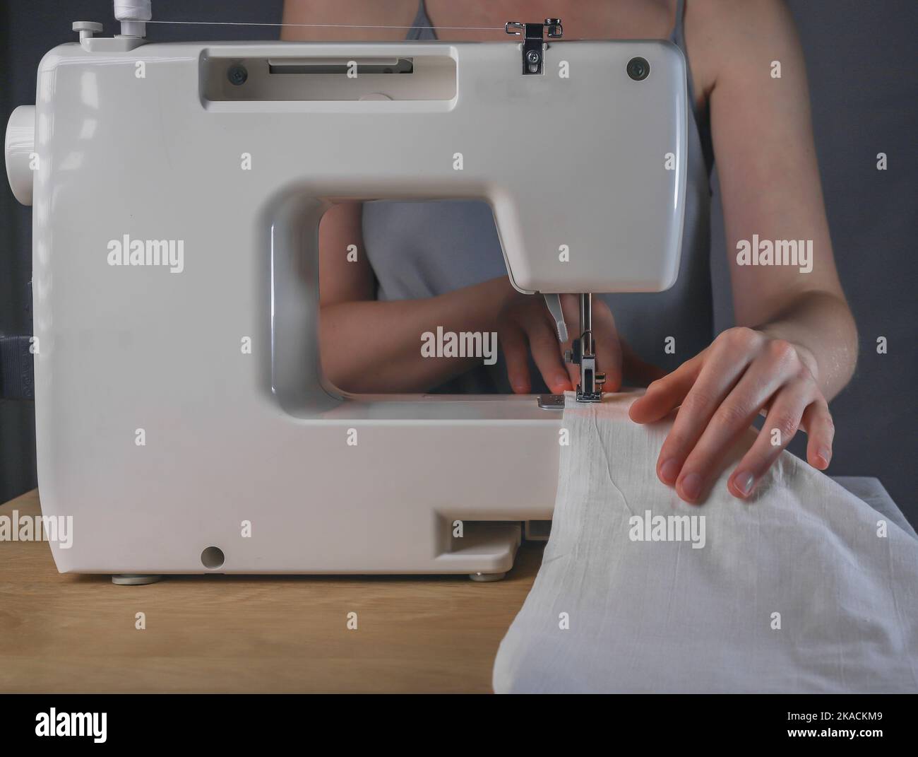 Seamstress hands with linen cloth at sewing machine, working process