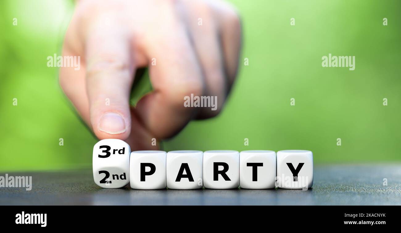 Hand turns dice and changes the expression '2nd party' to '3rd party'. Stock Photo