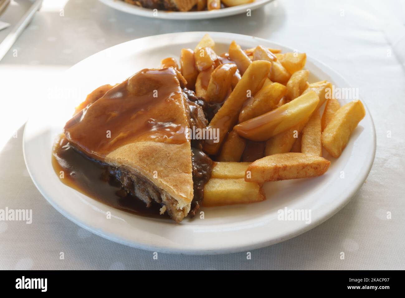 Savoury steak and ale meat pie with potato chips and gravy Stock Photo