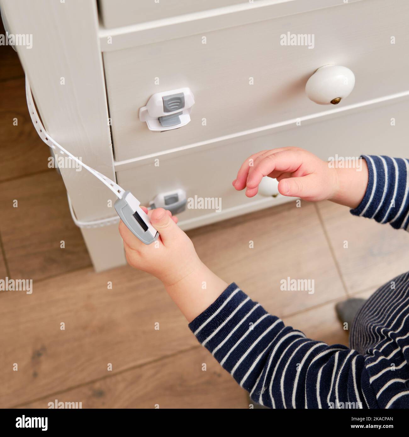 Baby opens the child lock on the closed drawer of the Toddler
